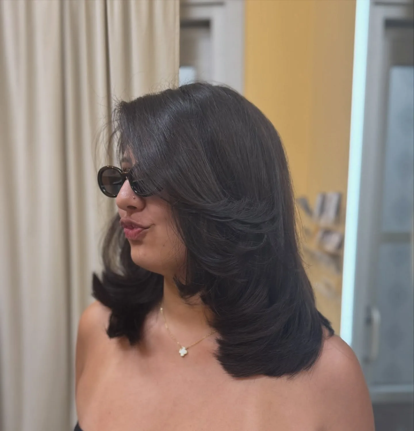 Dark shoulder-length hair styled in smooth, rounded layers.